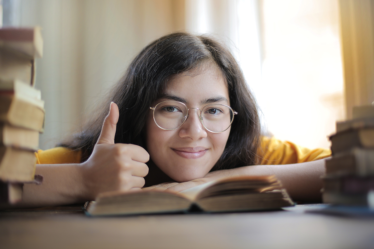 Woman giving thumbs up and reading book