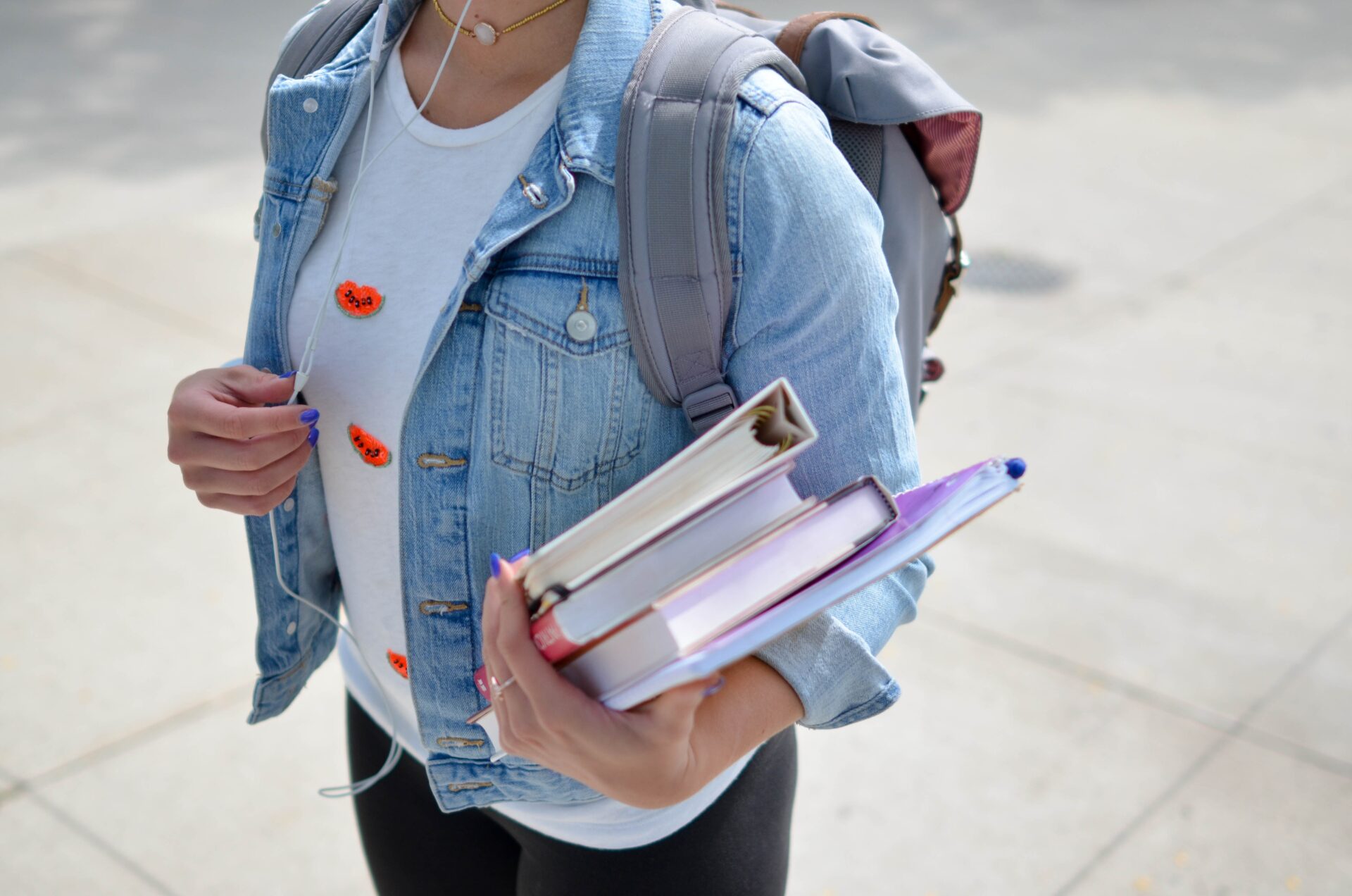 A student carrying a backpack and holding books