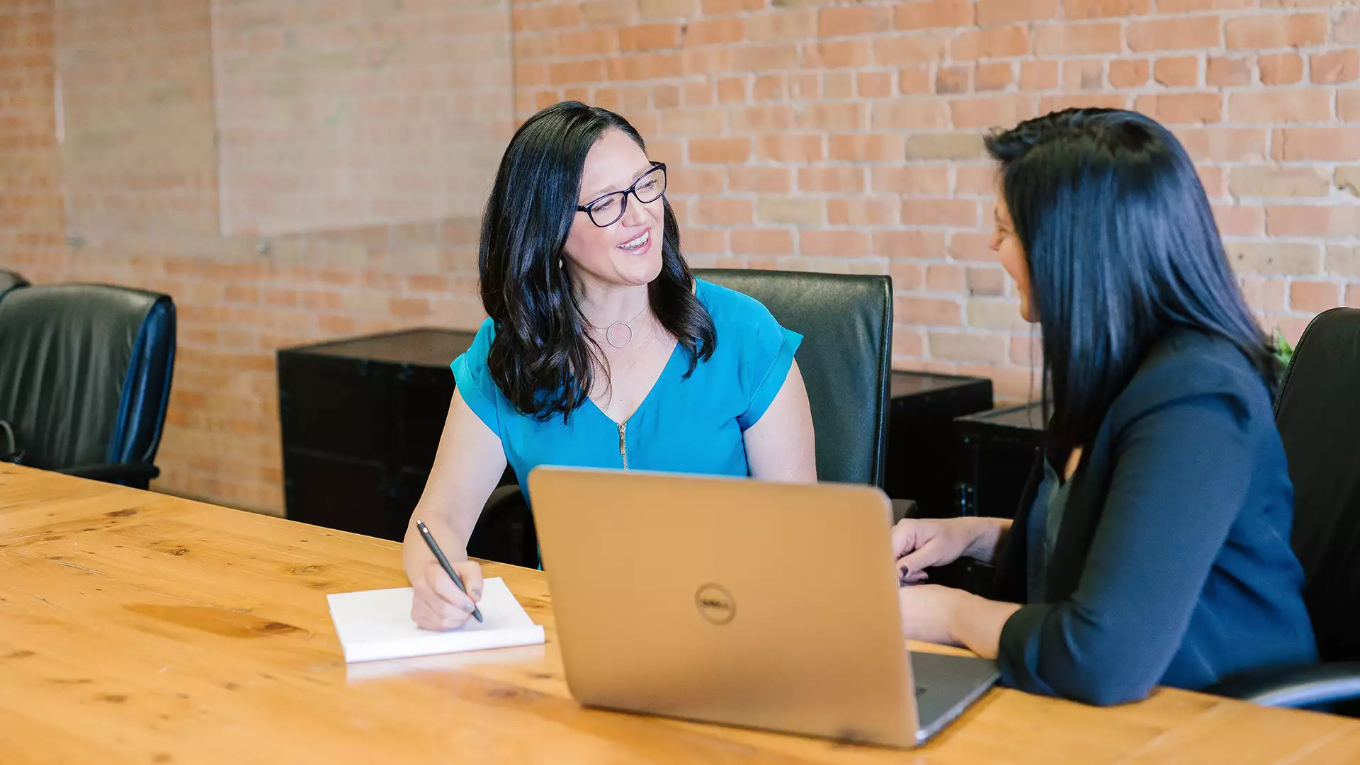 Two women talking to each other at a conference table